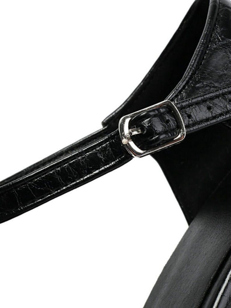 Close-up of a black leather strap with a silver buckle on a white background