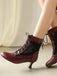 Red high-heeled shoes with lace-up design worn by a person sitting on a beige surface.