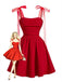 Une robe rouge vif de style vintage, cintrée et évasée, avec des épaules à nouer en ruban transparent et un corsage froncé, ornée d'une illustration de pin-up blonde.