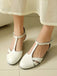 White sandals worn with a light-colored skirt on a neutral floor.