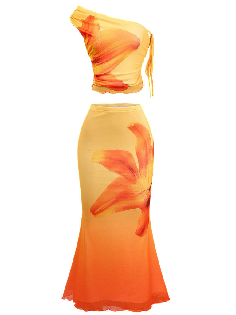 Front studio view of the orange floral set highlighting the asymmetrical neckline and the flared mermaid hem of the skirt.